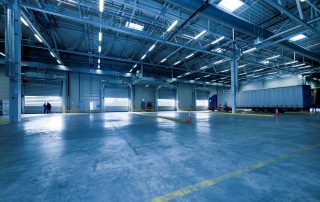 The inside of a warehouse with four roll-down bay doors and a large semi-truck