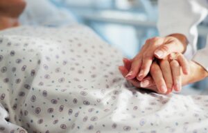 Hospital A doctor consoling a patient lying in a hospital bed and holding their hand